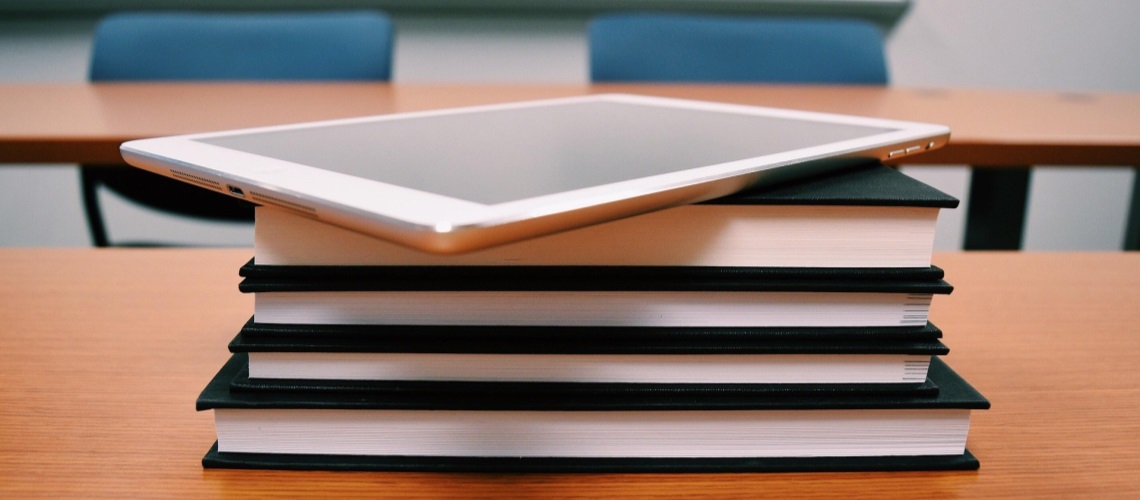 Bøker i stabel med iPad på toppen