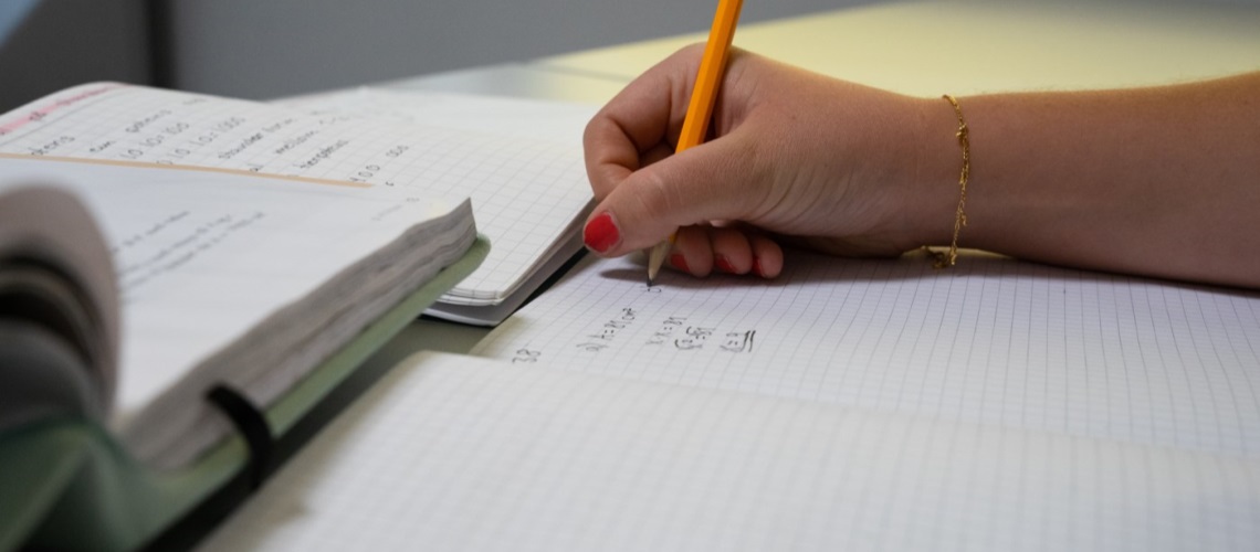 Bøker og elev som gjør notater i skrivebok